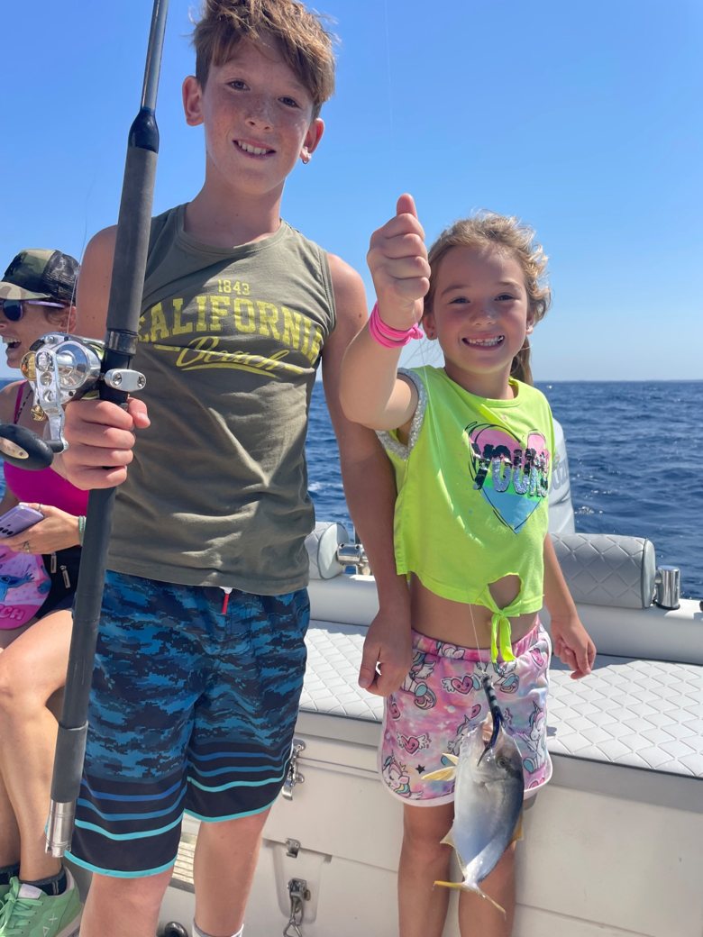 Due bambini con la canna da pesca a bordo del gommone